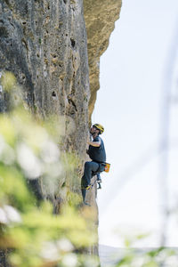 Active man rock climbing on sunny day