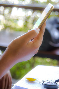 Cropped hand of man using smart phone over table