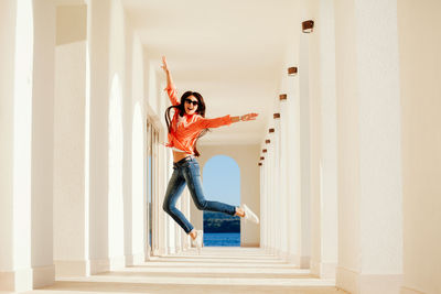 Portrait of young woman jumping in corridor