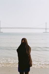 Woman standing at beach against clear sky