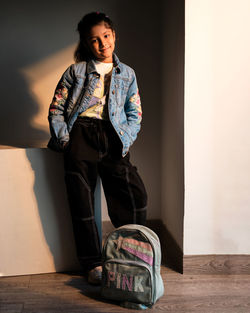 Portrait of young woman standing against wall