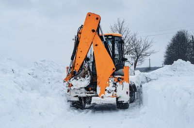 Big yellow tractor cleans up snow from road. cleaning and cleaning of roads in city from snow