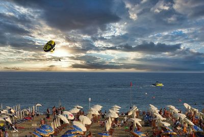 People at beach against cloudy sky