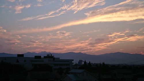 Silhouette houses against sky during sunset