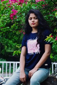 Portrait of young woman sitting against plants