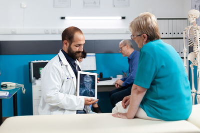 Doctor showing digital tablet to patient at clinic