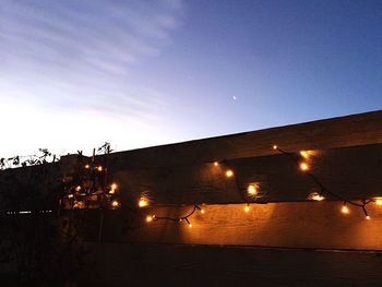 Illuminated street light against sky at night