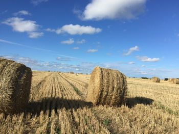 Hay bales on field against sky