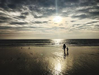 Silhouette person standing on beach against sky during sunset