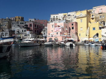 Boats moored in canal by buildings against sky in city