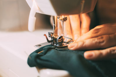 Cropped hand of woman holding sewing machine