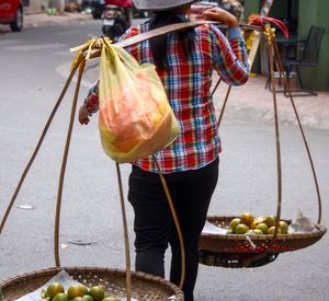 Rear view of woman selling fruits on carrying pole