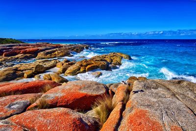 Rocks on beach against blue sky