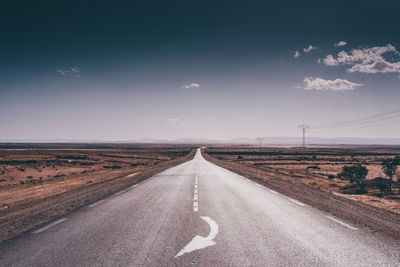 Surface level of empty road against cloudy sky