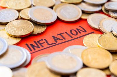 Word inflation on red surface, surrounded by euro coins. rising prices, economic repercussions.