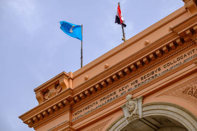 Low angle view of flags on building against sky