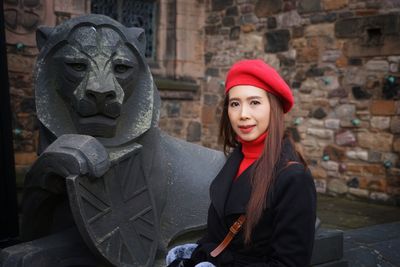 Portrait of woman standing against statue