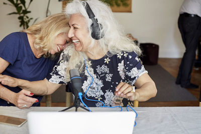 Cheerful senior friends vlogging through laptop at home