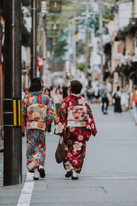 Rear view of people walking on road