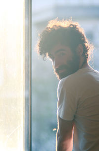 Portrait of young man looking through window