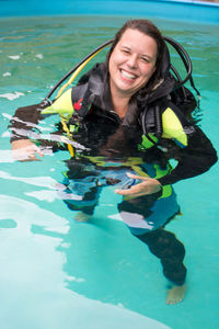Portrait of happy woman wearing diving suit in swimming pool