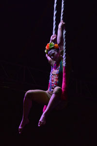 Midsection of woman dancing against black background