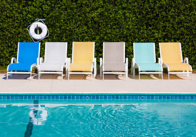 Chairs by swimming pool against trees