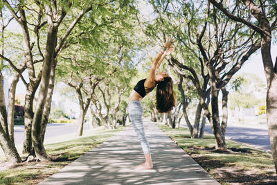 Side view of a woman doing yoga and stretching in a park 