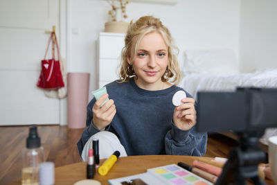 Portrait of young woman using mobile phone while sitting at home