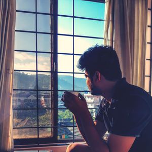 Portrait of young man looking through window