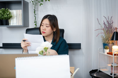 Businesswoman reading document while sitting at office