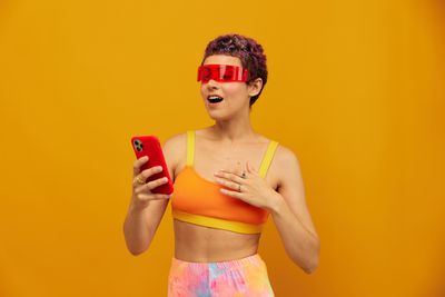 Portrait of young woman standing against yellow background