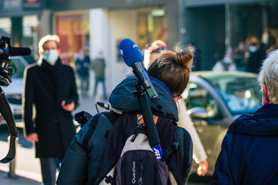 Rear view of people walking on street in city