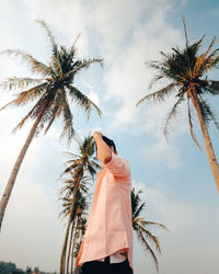Low angle view of woman standing by tree against sky