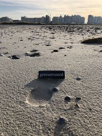 Text on sand at beach against sky