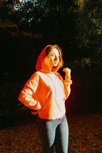 Midsection of woman standing by tree against orange sky