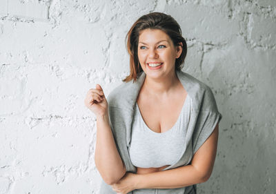 Portrait of a smiling young woman leaning against wall