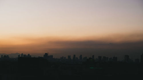 Silhouette of buildings in city during sunset