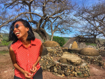 Young woman smiling while standing against trees