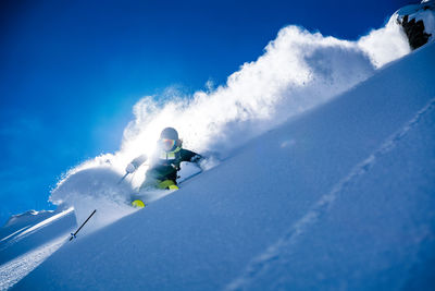 Woman skiing on snowcapped mountain against sky