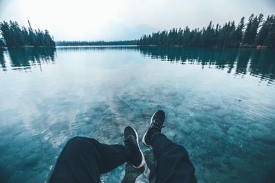 Low section of man standing by lake against sky