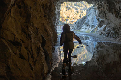 Rear view of woman standing in cave