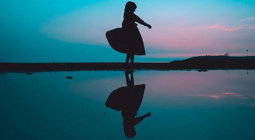 Silhouette woman at beach against sky at night