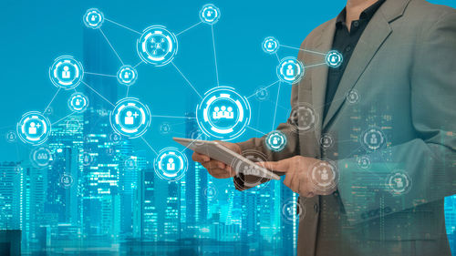 Digital composite image of businessman using digital tablet by various icons in city