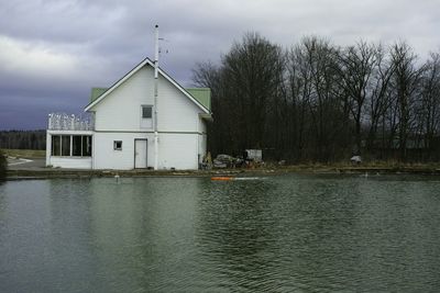 Houses by river against sky