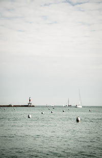 Sailboats sailing in sea against sky