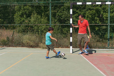 Father and son playing soccer on field