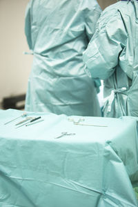 Midsection of doctors by medical tools on table in operating room