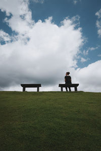 Rear view of woman sitting on grassy field