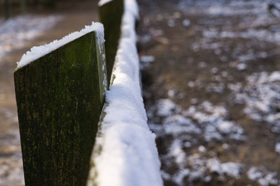 Close-up of frozen wooden post on snow